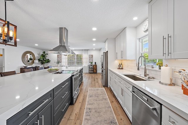 kitchen with island exhaust hood, decorative light fixtures, stainless steel appliances, and white cabinetry