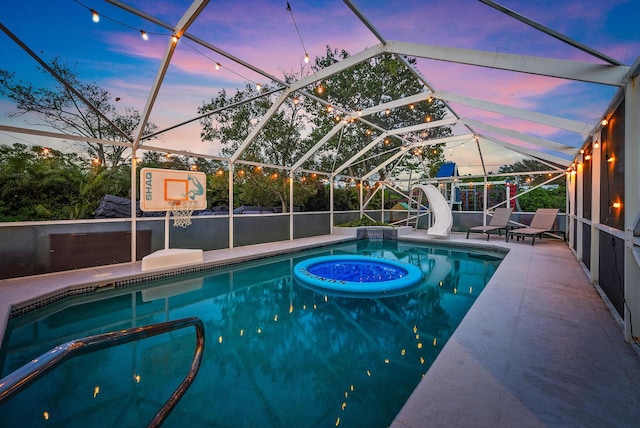 pool at dusk featuring a patio, a lanai, and a water slide