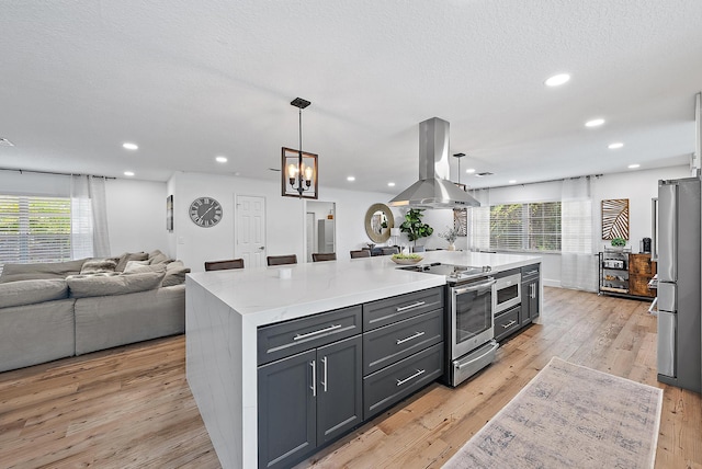 kitchen featuring island exhaust hood, stainless steel appliances, pendant lighting, light hardwood / wood-style floors, and plenty of natural light