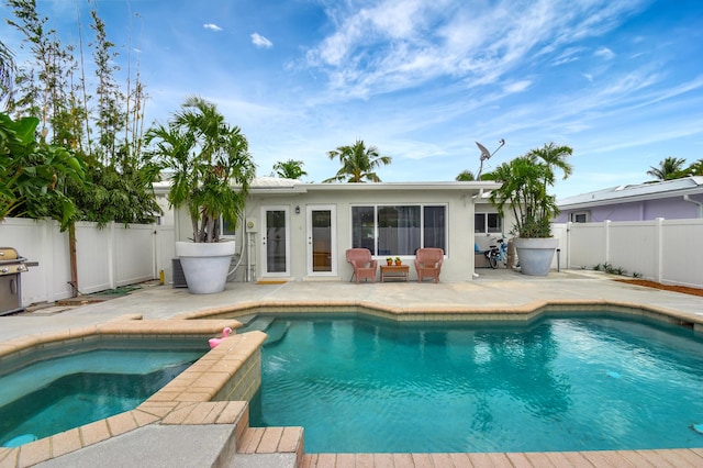 view of pool with an in ground hot tub, a grill, and a patio