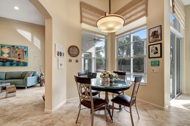 dining space with ceiling fan, crown molding, and light tile patterned floors