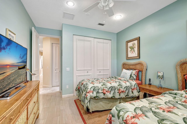 bedroom with ceiling fan, light wood-type flooring, a textured ceiling, and a closet