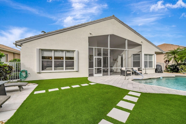 back of property featuring a patio, a fenced in pool, a sunroom, and a lawn