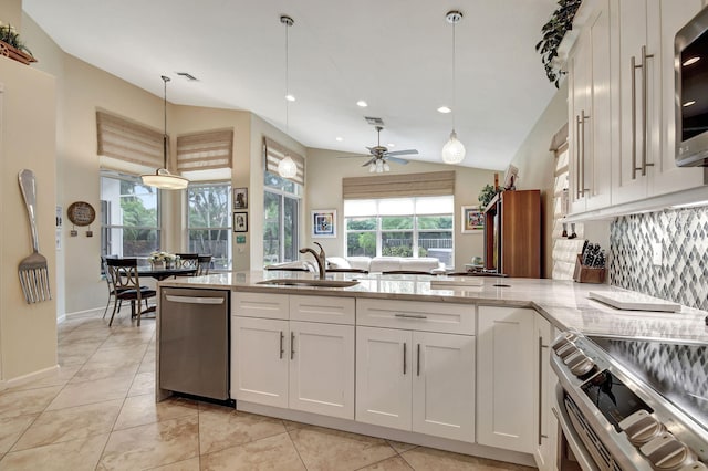 kitchen featuring pendant lighting, lofted ceiling, sink, appliances with stainless steel finishes, and white cabinetry