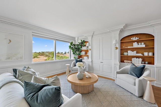 living room featuring built in shelves, crown molding, and light hardwood / wood-style flooring