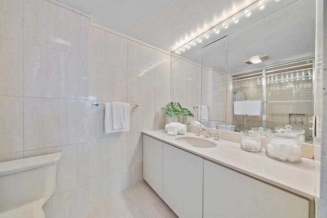 bathroom with tile patterned flooring, vanity, toilet, and tile walls