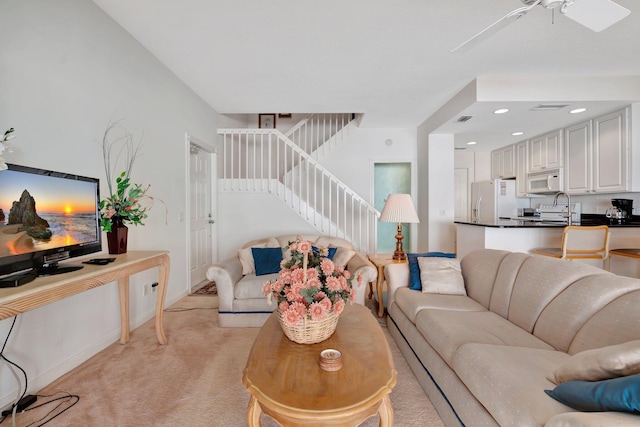 living room with ceiling fan, sink, and light carpet