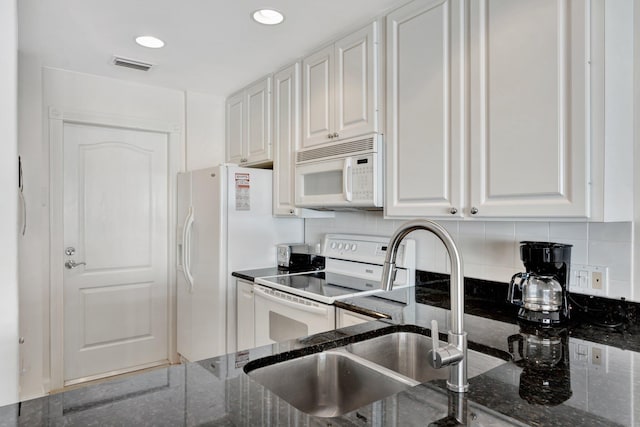 kitchen with tasteful backsplash, white appliances, sink, dark stone countertops, and white cabinets