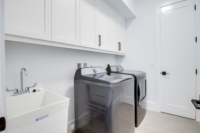 clothes washing area with cabinets, washer and dryer, and sink