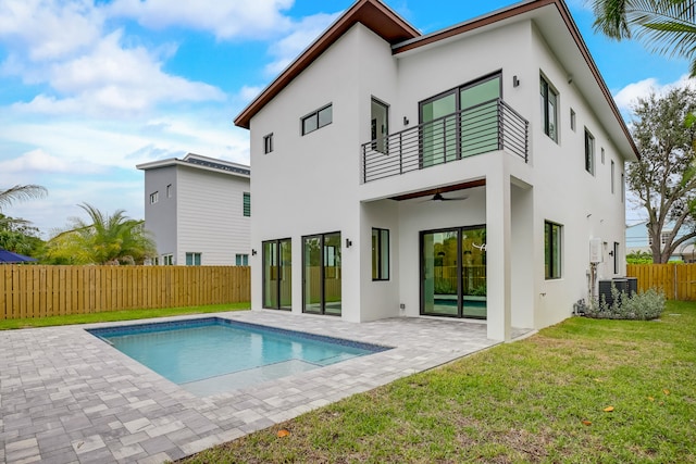 back of property with a balcony, a patio area, ceiling fan, and a fenced in pool