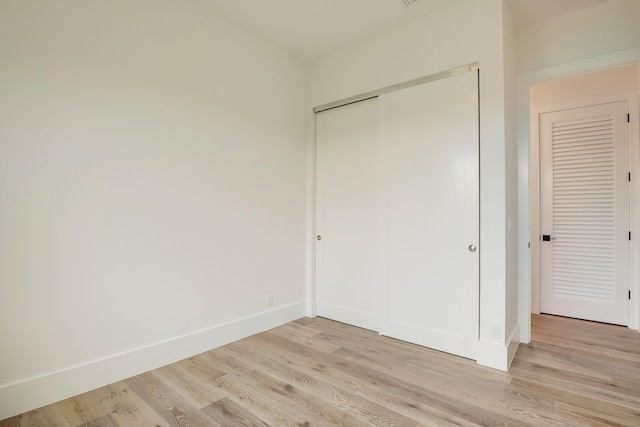 unfurnished bedroom with light hardwood / wood-style floors and a closet