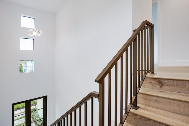 staircase with hardwood / wood-style floors, a healthy amount of sunlight, and a notable chandelier