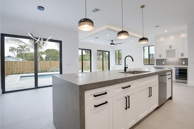 kitchen featuring white cabinetry, a wealth of natural light, a kitchen island with sink, and sink