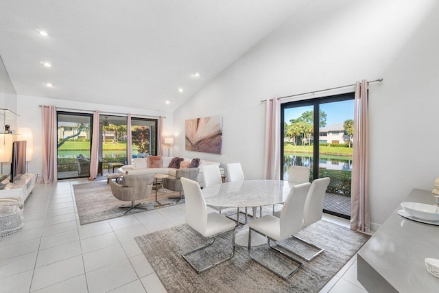 tiled dining space with a water view and high vaulted ceiling