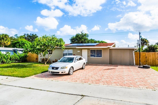 ranch-style house featuring solar panels and a front lawn