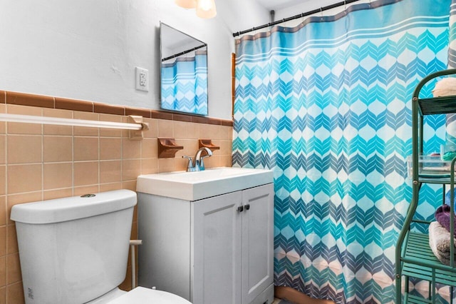 bathroom with curtained shower, vanity, tile walls, and toilet