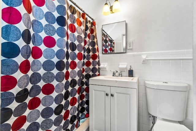 bathroom with vanity, toilet, tile walls, and walk in shower