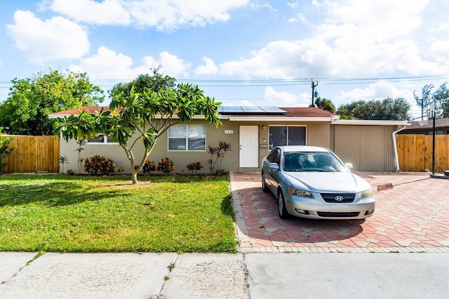 single story home featuring a front yard and solar panels