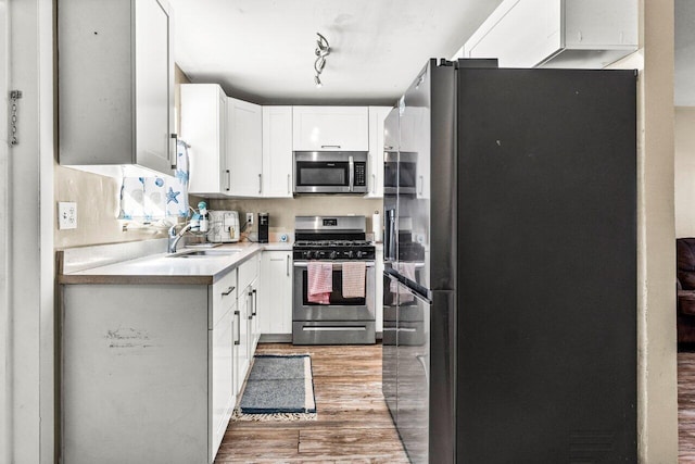 kitchen featuring backsplash, sink, light hardwood / wood-style flooring, appliances with stainless steel finishes, and white cabinetry