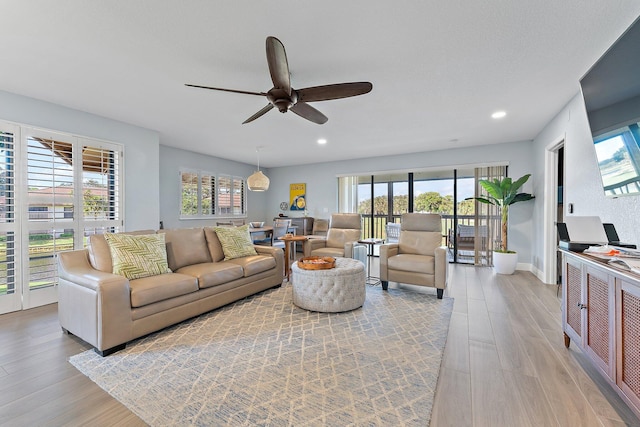 living room featuring ceiling fan, a healthy amount of sunlight, and light wood-type flooring