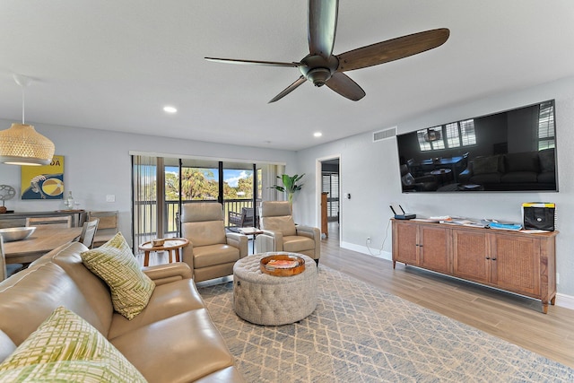 living room with light hardwood / wood-style flooring and ceiling fan