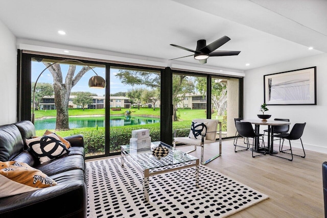 living room with ceiling fan, light hardwood / wood-style floors, and a water view