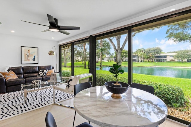 sunroom with ceiling fan, a healthy amount of sunlight, and a water view