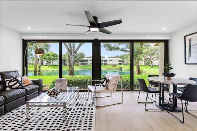 sunroom / solarium featuring a water view and ceiling fan