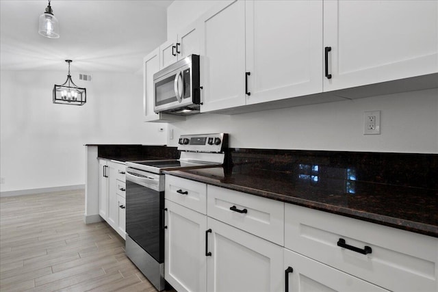 kitchen featuring pendant lighting, white cabinets, stainless steel appliances, and light hardwood / wood-style floors