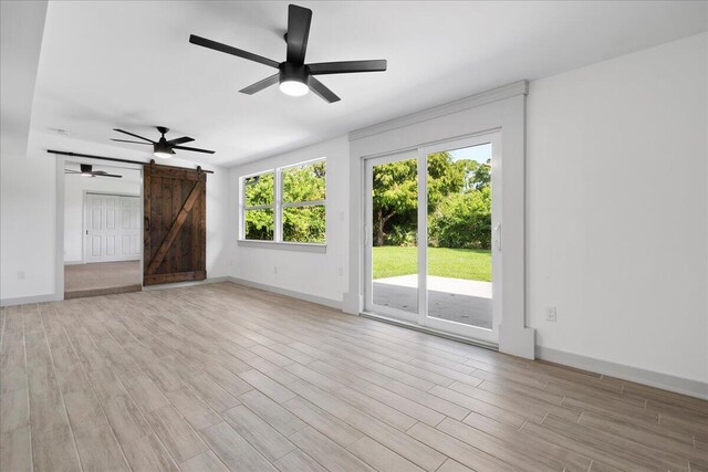 810 Bradley St, Fort Pierce, FL 34982 - unfurnished living room with a barn door, light wood-style flooring, ceiling fan, and baseboards