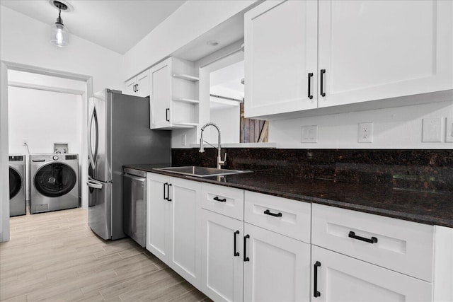 kitchen featuring white cabinets, sink, light hardwood / wood-style flooring, stainless steel dishwasher, and washing machine and dryer