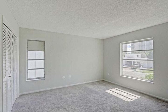 carpeted empty room with a textured ceiling