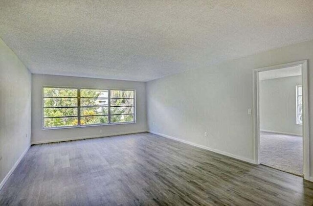 unfurnished room with dark hardwood / wood-style flooring and a textured ceiling