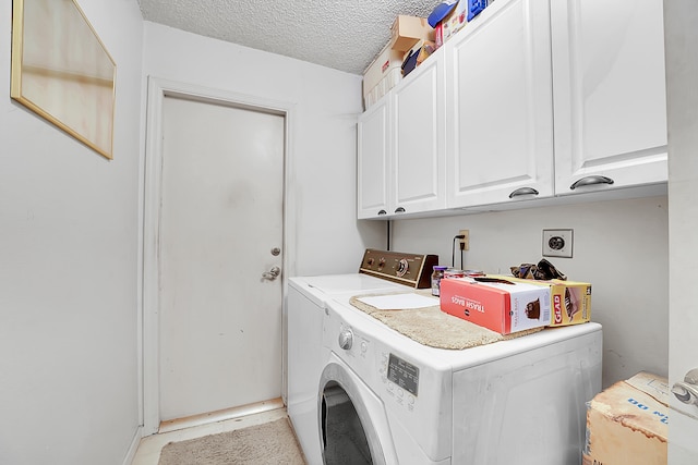 laundry area featuring washer and dryer, cabinets, and a textured ceiling