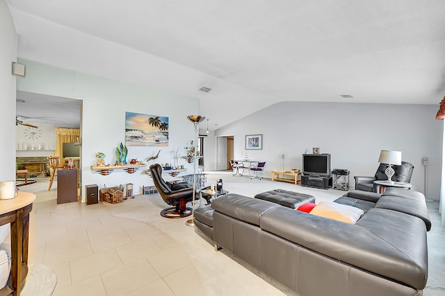 tiled living room featuring ceiling fan, lofted ceiling, and a fireplace