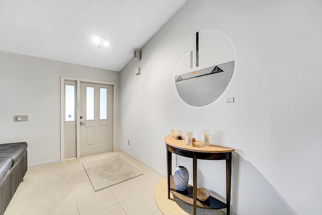 foyer entrance with light tile patterned flooring, a textured ceiling, and vaulted ceiling