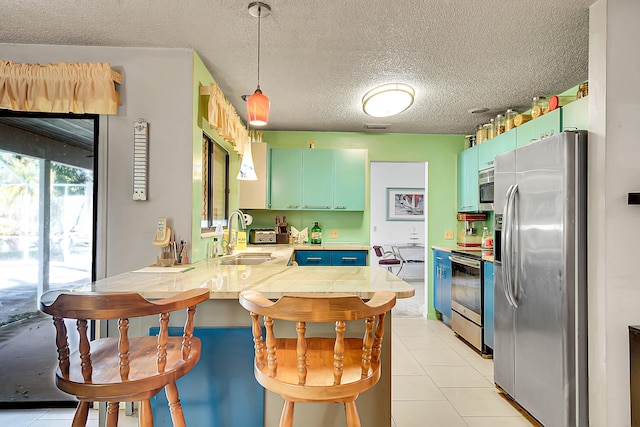 kitchen with sink, stainless steel appliances, kitchen peninsula, a textured ceiling, and light tile patterned flooring