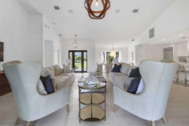 living area featuring high vaulted ceiling, visible vents, and french doors