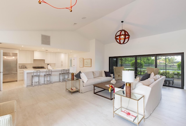 living room with high vaulted ceiling and a notable chandelier