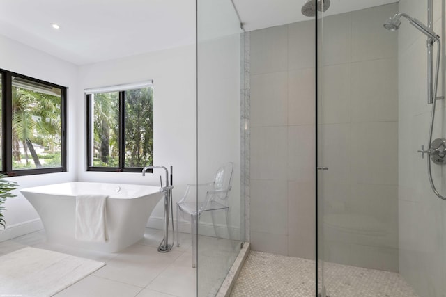 full bath with a freestanding bath, tile patterned flooring, a shower stall, and baseboards