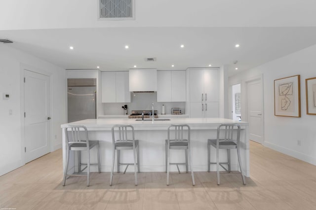 kitchen with light countertops, visible vents, white cabinetry, an island with sink, and modern cabinets