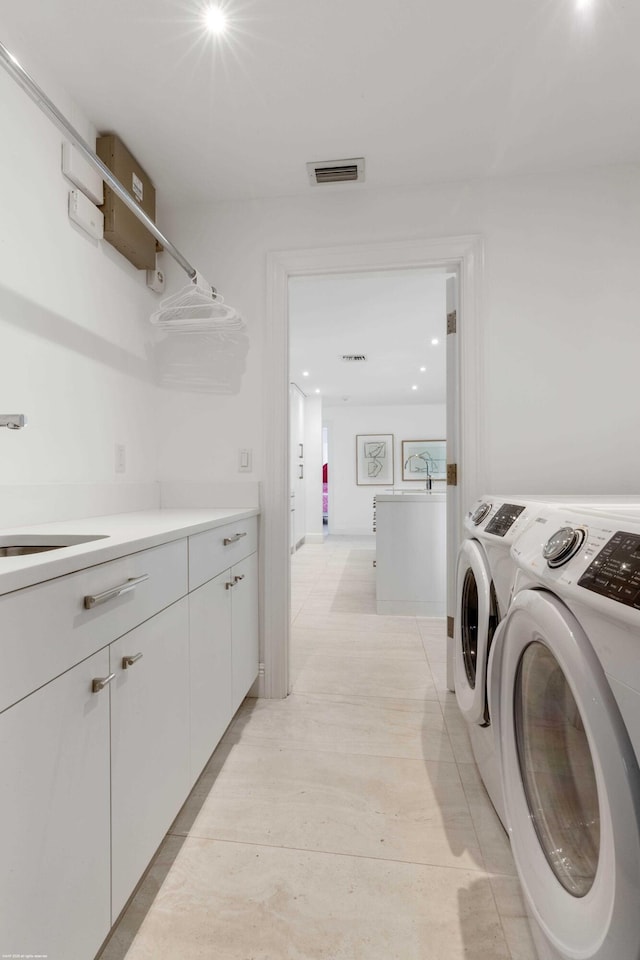 laundry room featuring cabinet space, visible vents, washer and clothes dryer, and a sink