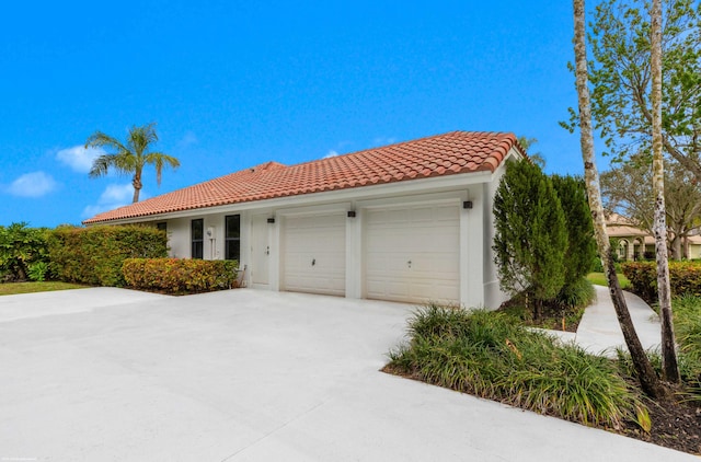 mediterranean / spanish-style house with a garage, stucco siding, driveway, and a tiled roof