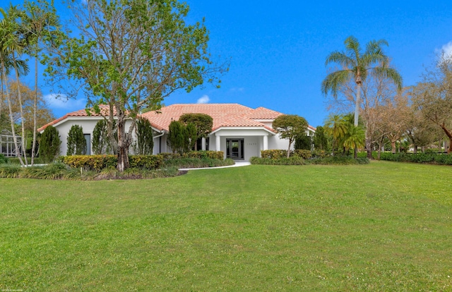 view of front of home with stucco siding, a tile roof, and a front yard