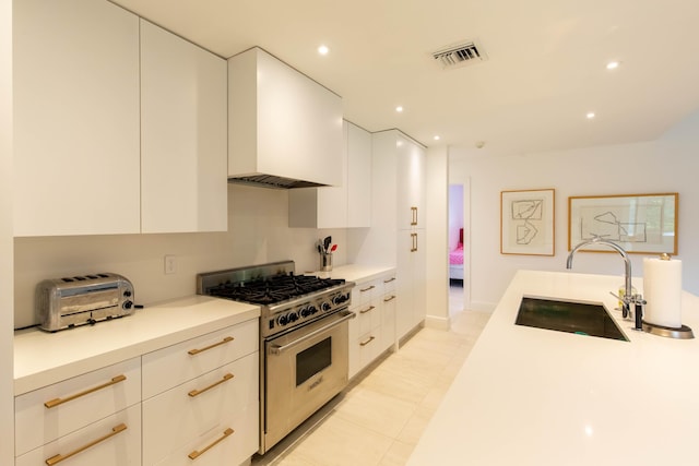 kitchen featuring white cabinetry, sink, stainless steel stove, and custom range hood