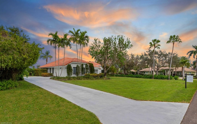 view of home's community with concrete driveway and a lawn