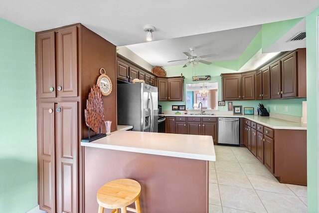 kitchen with kitchen peninsula, a kitchen breakfast bar, stainless steel appliances, sink, and light tile patterned flooring