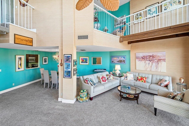 living room featuring carpet, a towering ceiling, beam ceiling, and a notable chandelier