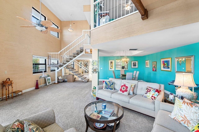 carpeted living room with ceiling fan with notable chandelier, beam ceiling, and a towering ceiling