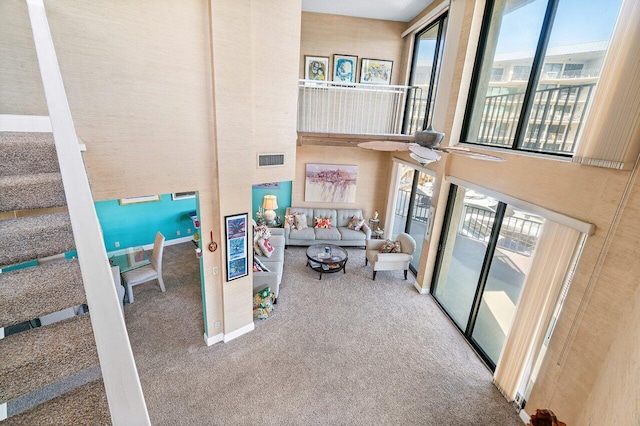 living room featuring carpet, a towering ceiling, and a wealth of natural light